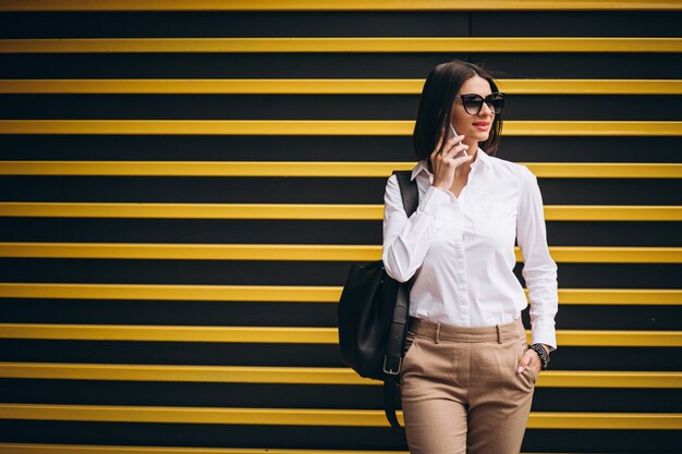 Donna che fa una pausa la parete gialla e che parla sul telefono