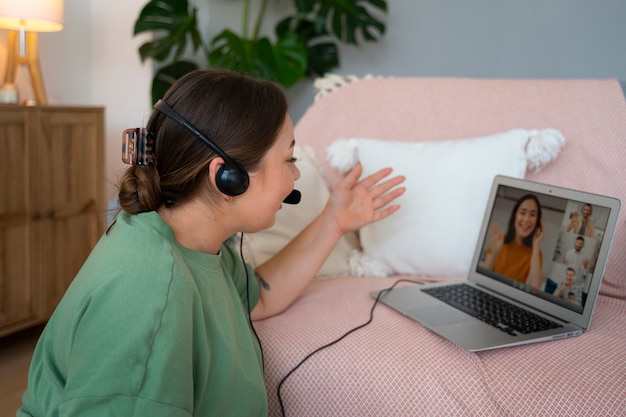 Donna che fa una videochiamata a casa su un portatile con cuffie