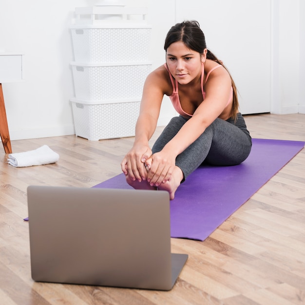 Donna che fa yoga con il computer portatile