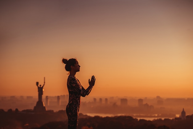 Donna che fa yoga sul tetto di un grattacielo in grande città.