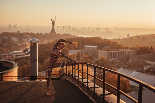 Donna che fa yoga sul tetto di un grattacielo in grande città