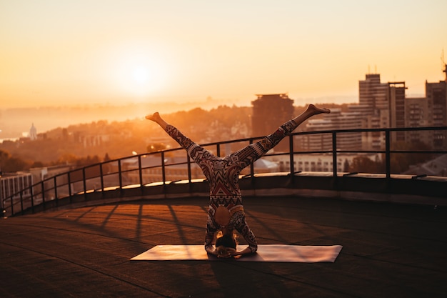 Donna che fa yoga sul tetto di un grattacielo in grande città.