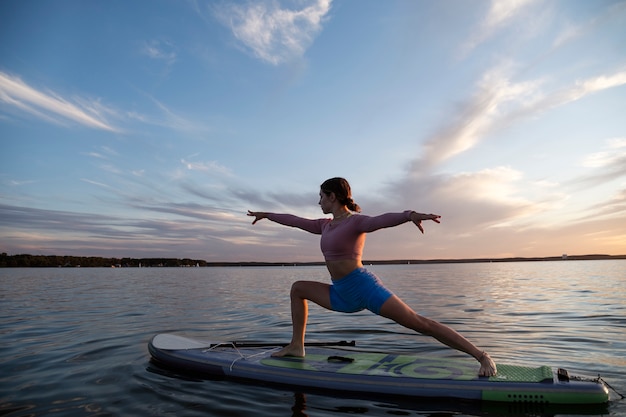 Donna che fa yoga sulla vista laterale del paddleboard