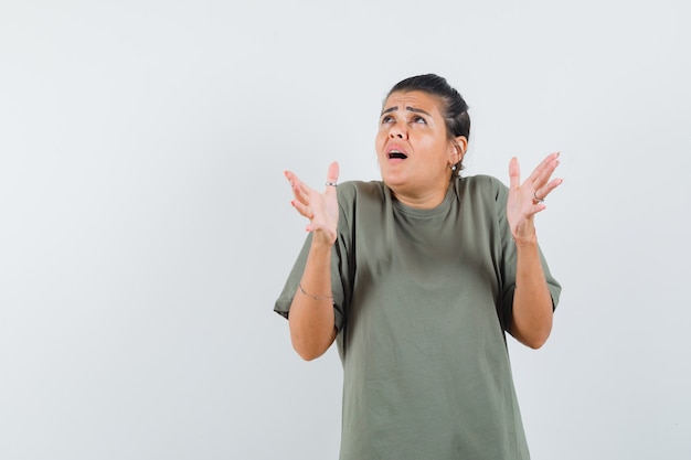 donna che finge di tenere qualcosa in t-shirt e sembra allarmata