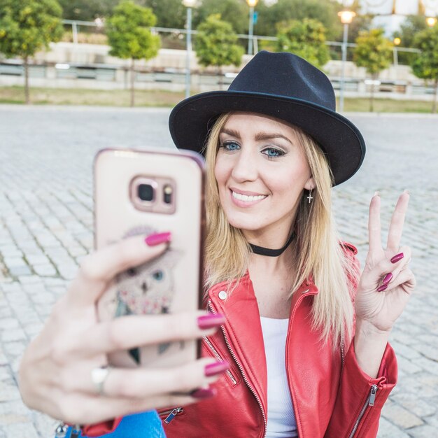 Donna che gesturing pace e prendendo selfie