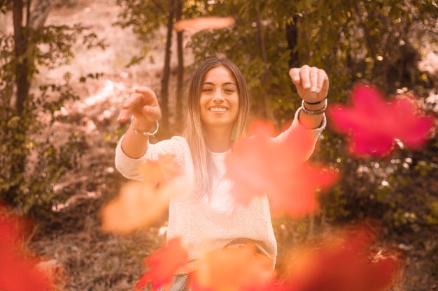 Donna che getta le foglie d&#39;autunno alla macchina fotografica