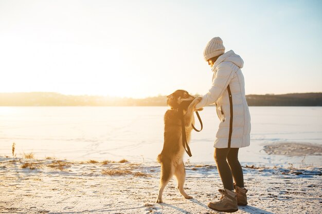 Donna che gioca con il suo cane in una giornata invernale