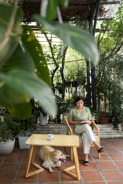 Donna che gode di un libro in giardino insieme al suo cane