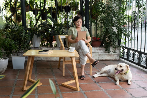 Donna che gode di un libro in giardino insieme al suo cane