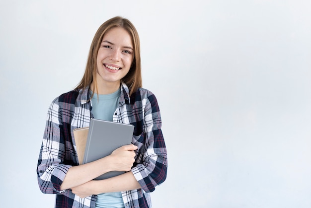 Donna che guarda l'obbiettivo mentre si tiene alcuni libri