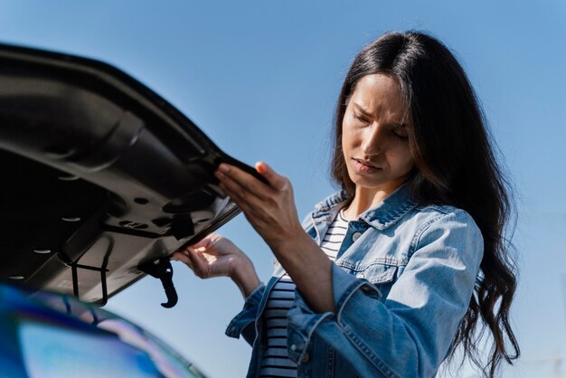 Donna che guarda la sua auto per risolvere un problema