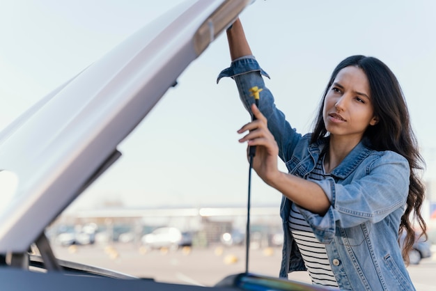 Donna che guarda la sua auto per risolvere un problema