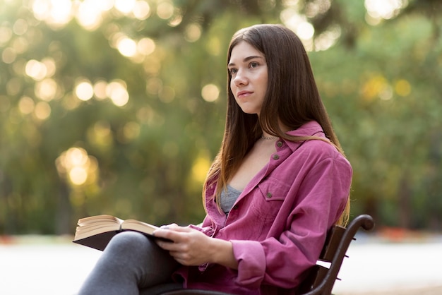 Donna che guarda lontano mentre si tiene un libro