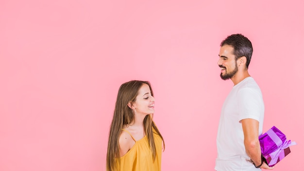 Donna che guarda uomo che nasconde il regalo da lei