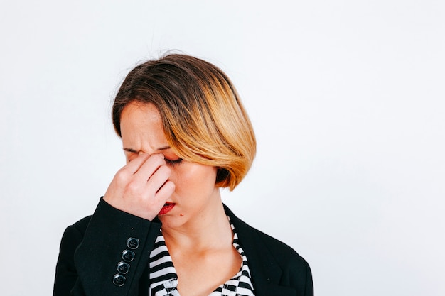 Donna che ha emicrania sfregando il naso