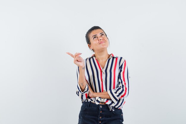 donna che indica da parte in camicia, gonna e che sembra sognante