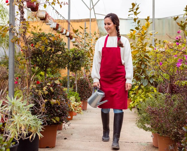 Donna che indossa abiti da giardinaggio a piedi in serra