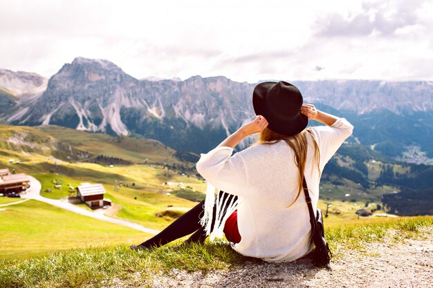 Donna che indossa abiti eleganti boho, cammina da sola e gode di una vista mozzafiato sulle montagne alpine austriache
