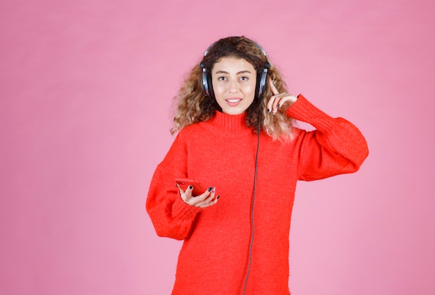 donna che indossa le cuffie che ascolta la sua playlist sullo smartphone e balla.