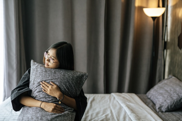 Donna che indossa un abito nero, abbracciando il cuscino nel letto.