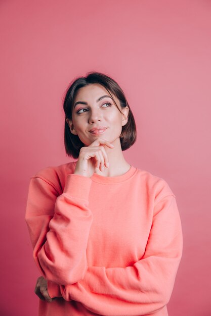 Donna che indossa un maglione casual sulla mano di sfondo sul mento pensando alla domanda, espressione pensierosa. Sorridendo con una faccia pensierosa