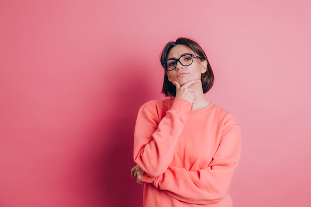 Donna che indossa un maglione casual sullo sfondo pensando preoccupato per una domanda, preoccupato e nervoso con la mano sul mento