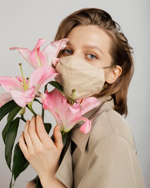 Donna che indossa una maschera e azienda bouquet di fiori