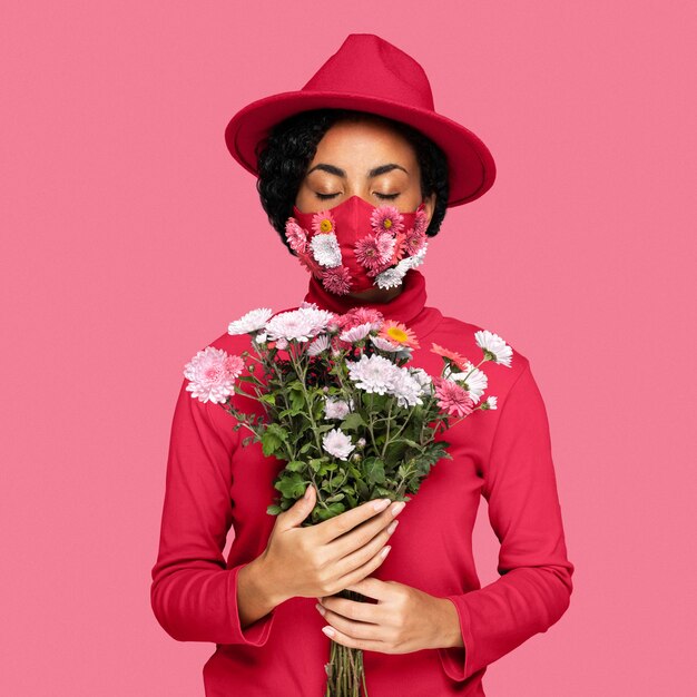 Donna che indossa una maschera facciale con in mano un bouquet del colore dell'anno 2023