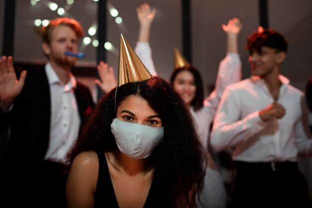 Donna che indossa una maschera medica accanto ai suoi amici alla festa di capodanno