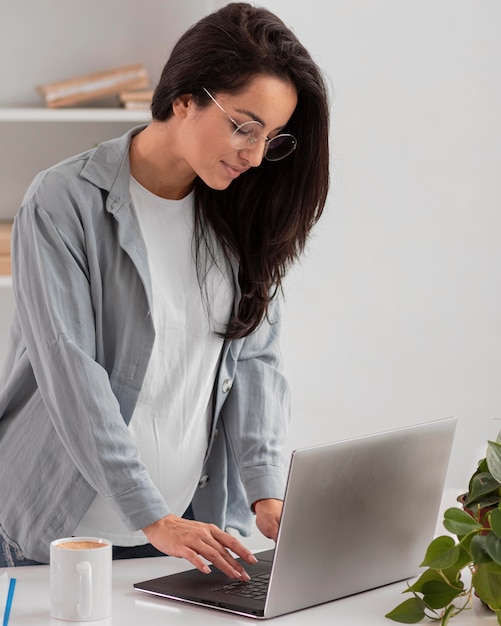 Donna che lavora al computer portatile a casa durante la gravidanza