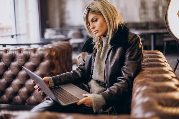 Donna che lavora al computer portatile in un bar e allenatore seduto