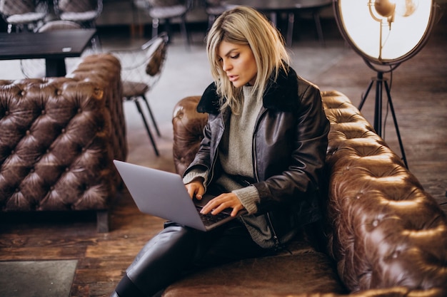 Donna che lavora al computer portatile in un bar e allenatore seduto