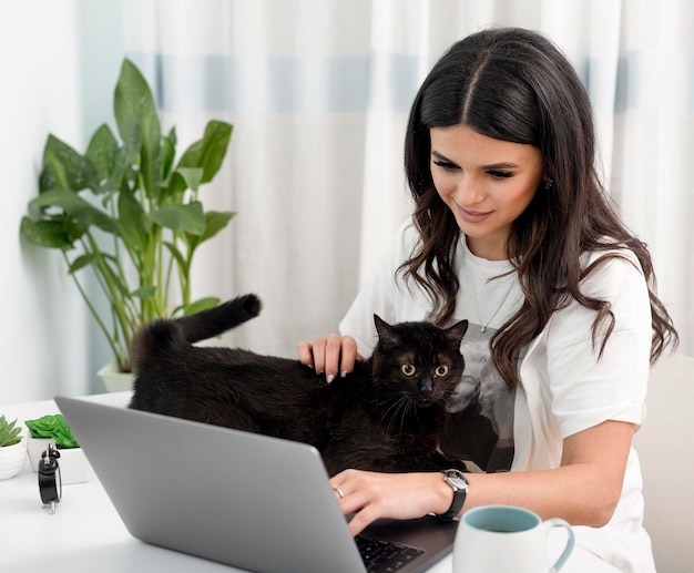 Donna che lavora come libero professionista e che gioca con il gatto