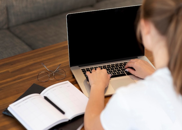 Donna che lavora da casa per allontanamento sociale con notebook e laptop