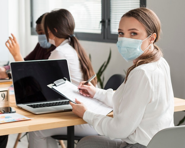 Donna che lavora in ufficio durante la pandemia con la maschera