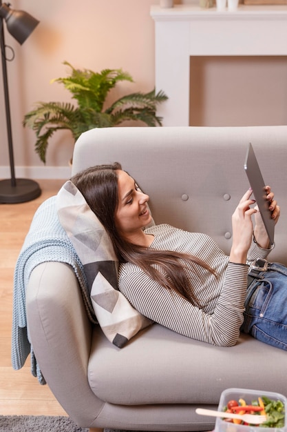 Donna che lavora su tavoletta digitale e cibo sul tavolo