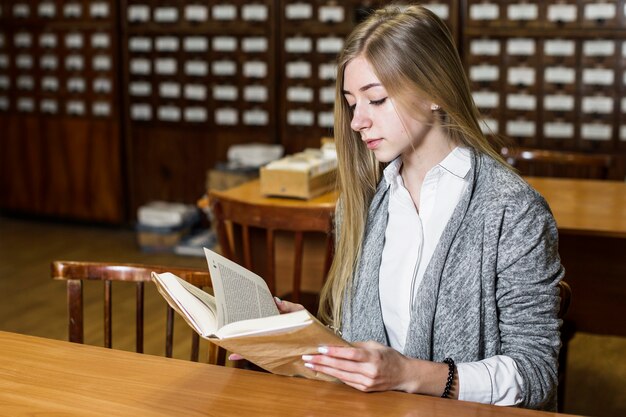 Donna che legge al tavolo della biblioteca