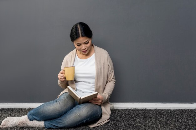 Donna che legge e che beve caffè