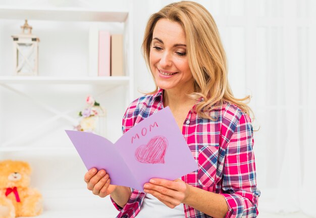 Donna che legge la cartolina d&#39;auguri con iscrizione mamma