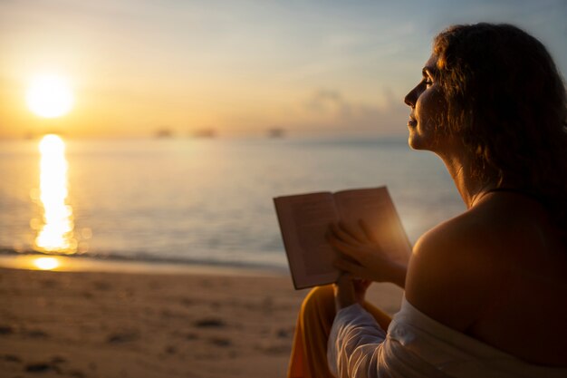 Donna che legge sulla vista laterale della spiaggia