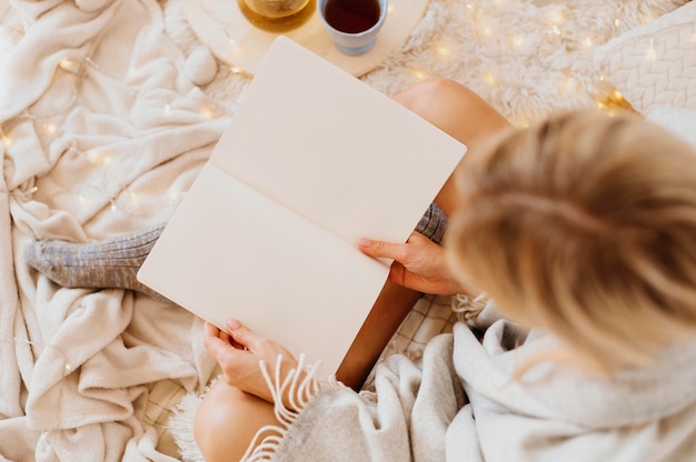 Donna che legge un libro mentre si gode le vacanze invernali