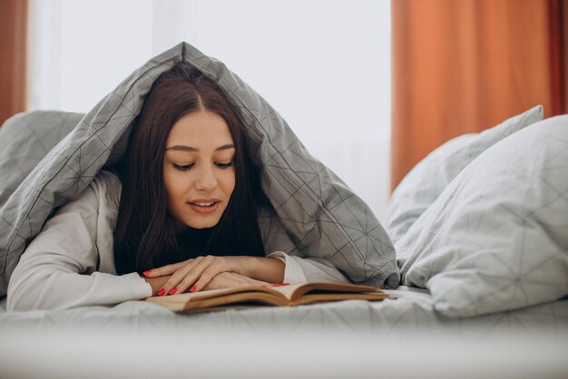 Donna che legge un libro nel suo letto