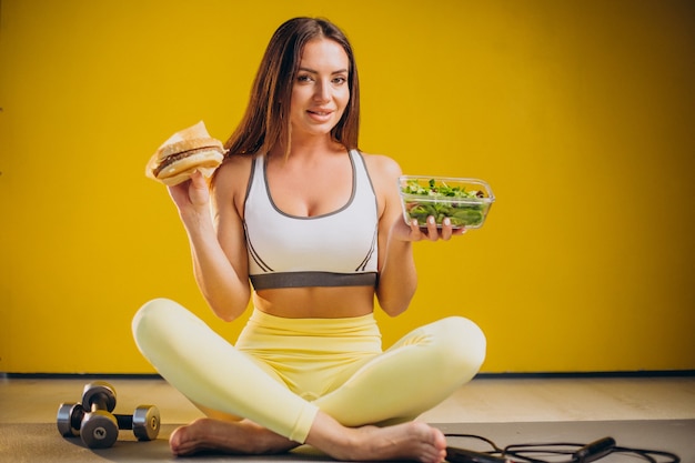 Donna che mangia insalata isolata su sfondo giallo