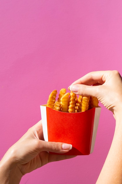 Donna che mangia le patate fritte dalla scatola rossa