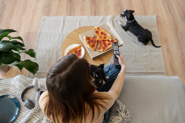 Donna che mangia pizza e guarda la tv