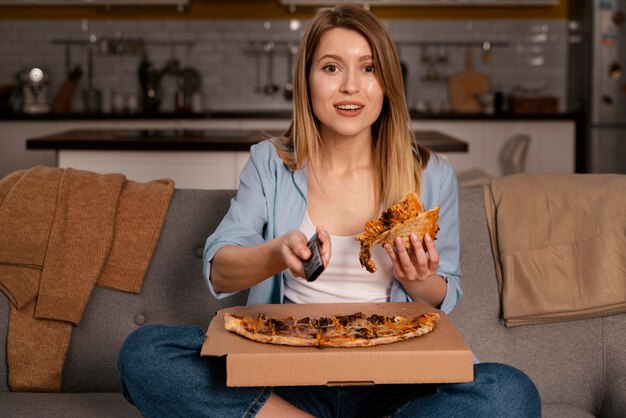 Donna che mangia pizza mentre si guarda la tv