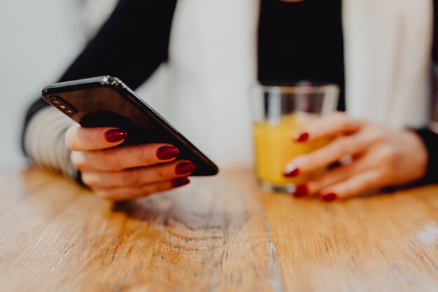 Donna che mangia un bicchiere di succo e controlla il suo telefono