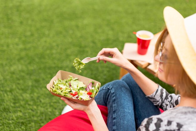 Donna che mangia un'insalata in parco