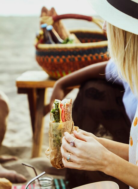 Donna che mangia un panino in un picnic sulla spiaggia