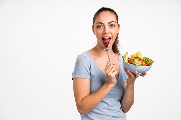 Donna che mangia un pomodoro con la forcella